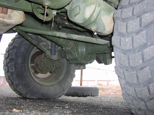 Undercarriage view of a military vehicle's rear axle, suspension, and large tire