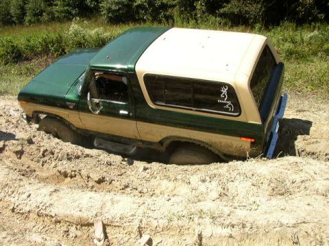 1995 Ford Bronco - This classic Ford Bronco is deeply mired in thick mud, with only its upper body visible.
