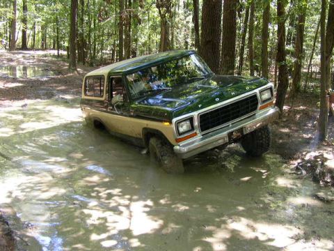 1995 Ford Bronco - This 1978 Ford Bronco is shown off-road, driving through a muddy patch in a wooded area.
