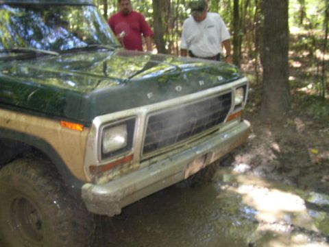 1995 Ford Bronco - Front view of a classic Ford truck with wood paneling, stuck in a muddy area.