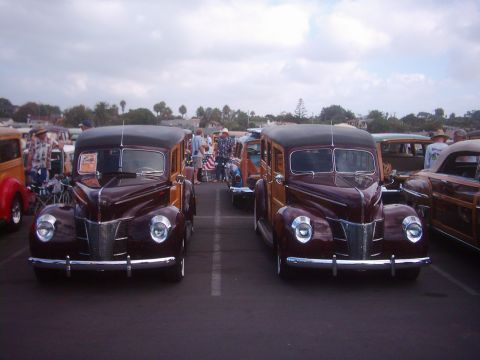 1978 Ford Bronco - Two vintage woodie station wagons are parked in a lot under a cloudy sky.