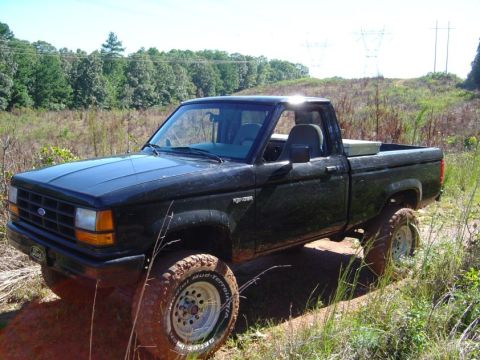 1989 Ford Ranger - A black 1989 Ford Ranger pickup truck is shown off-road on a sunny day.