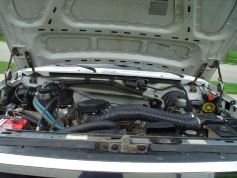 1993 Ford Bronco - The engine compartment of a vehicle is shown with the hood raised, revealing the motor and related parts.