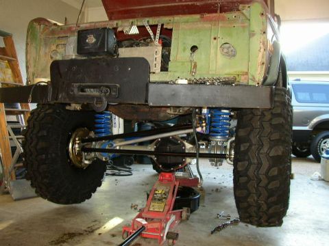 1995 Ford Bronco - A heavily modified Ford Bronco is undergoing repairs, showing its lifted suspension and large off-road tires.