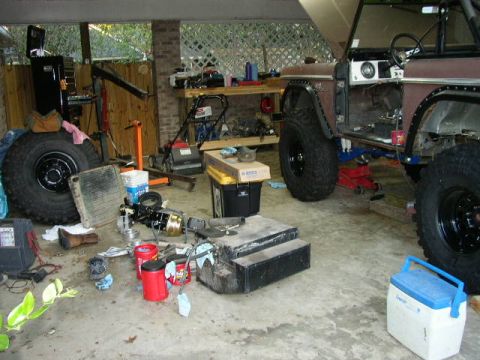 1995 Ford Bronco - A 1978 Ford Bronco is disassembled in a garage, with various parts and tools around it.