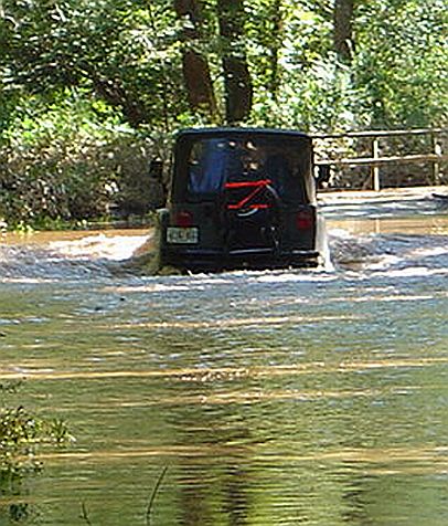 1989 Ford Ranger - SUV navigates through a flooded area with trees and a wooden fence in the background.