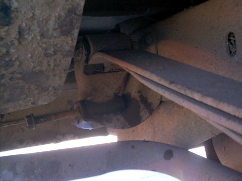 1995 Ford Bronco - Underbody shot looking up at a truck's solid front axle housing and differential, with the tie rod and track bar crossing the frame and day…