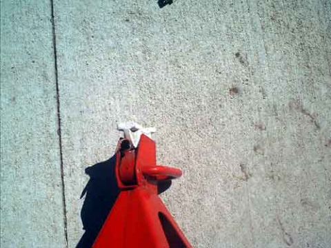1995 Ford Bronco - Overhead view of a red steel jack stand standing on a concrete driveway, its ratcheting post raised with the release handle and toothed rac…