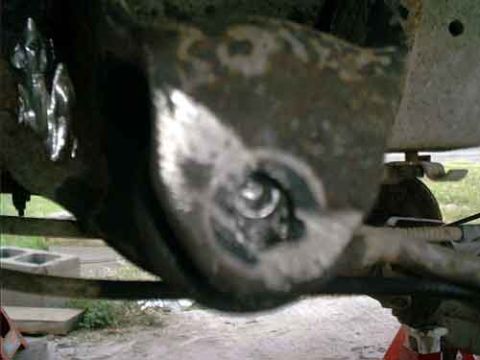 1995 Ford Bronco - Blurry close-up taken from underneath a raised vehicle, looking at a rusty axle housing and differential area with a shiny worn spot around…