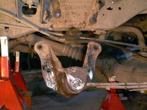 1995 Ford Bronco - Underside view of a truck/SUV chassis showing a heavy welded steel bracket or crossmember with fresh weld beads at the front axle area. The…