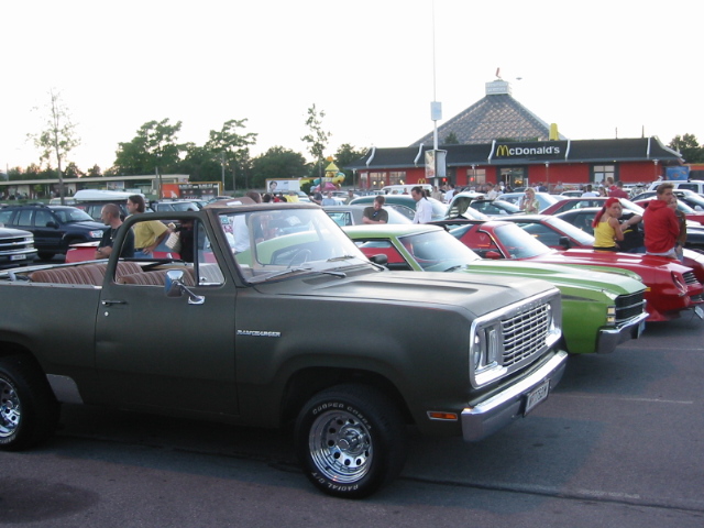 Olive green Dodge Ramcharger SUV parked in a lot with other cars, McDonald's in background