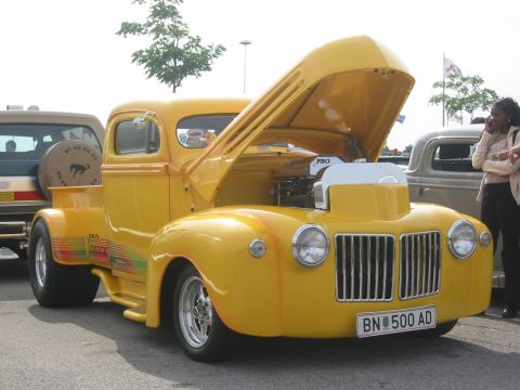 1992 Ford Crown Victoria - A yellow pickup truck is parked outside with its hood open, revealing the engine.