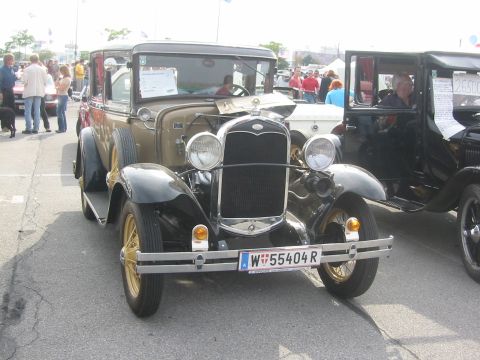 1992 Ford Crown Victoria - A vintage Ford Model A is parked on asphalt, with other vehicles and people in the background.