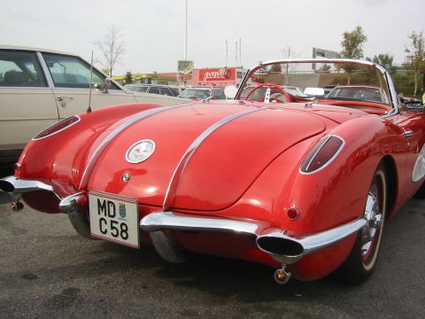 1992 Ford Crown Victoria - A classic red Chevrolet Corvette convertible is parked next to another car, showing its distinctive rear design.