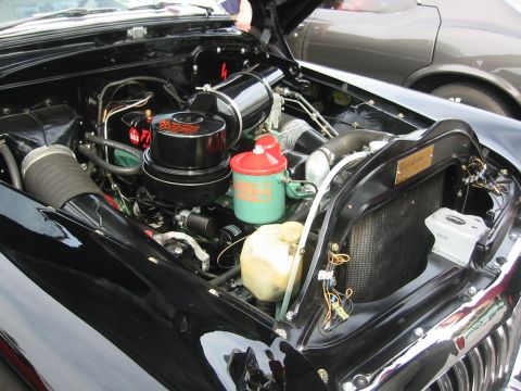 1992 Ford Crown Victoria - The engine bay of a classic car features a prominent black air cleaner and a red-topped reservoir, with another vehicle partially visible i…