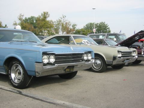1992 Ford Crown Victoria - Several classic cars are parked in a row, with the front of a light blue car prominently displayed.