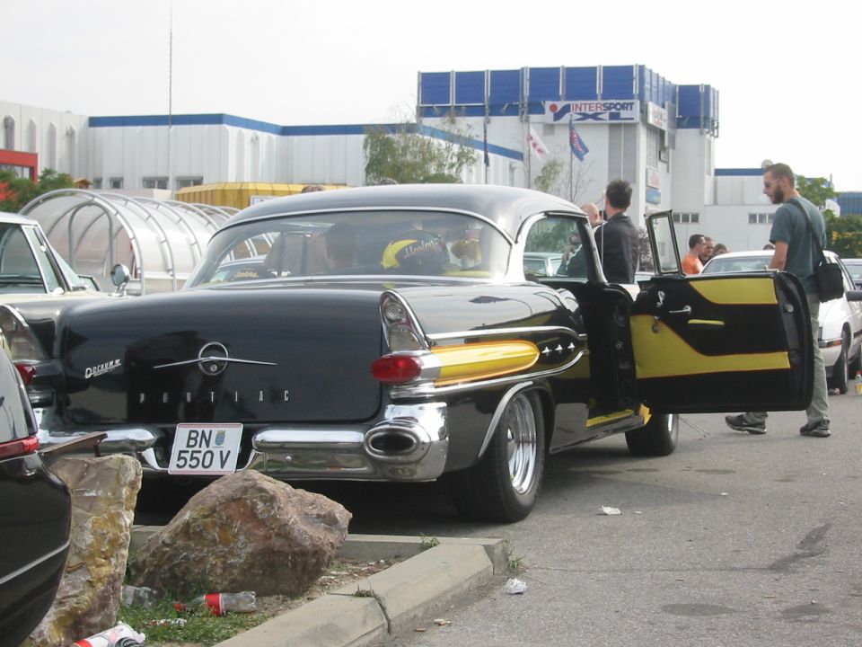 Black 1957 Pontiac Star Chief with yellow accents, rear view, driver's door open