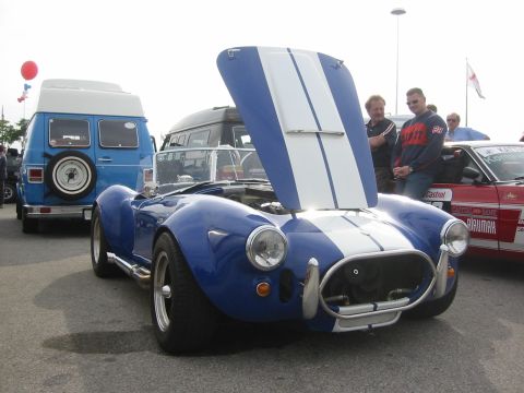 1992 Ford Crown Victoria - A blue AC Cobra replica is displayed with its hood open at an outdoor car show.