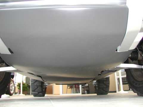 1985 Ford Bronco - The undercarriage of a vehicle is visible, with large tires and protective skid plates.