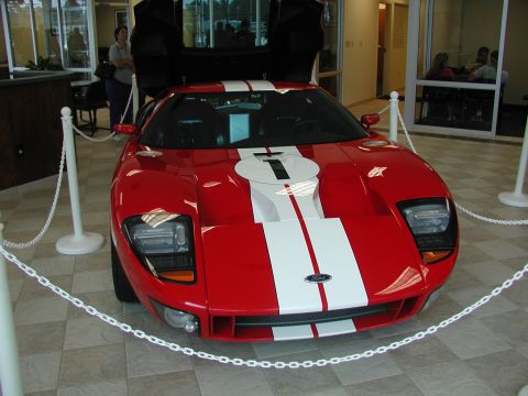 1985 Ford Bronco - A red and white striped Ford GT is displayed indoors with its doors open.