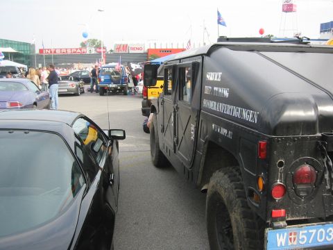 1992 Ford Crown Victoria - A black Humvee is parked next to a black sports car at an outdoor event.