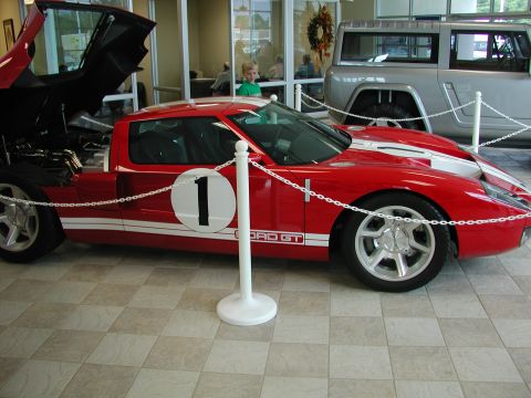 1985 Ford Bronco - A red Ford GT is displayed indoors with its hood open, next to another vehicle.