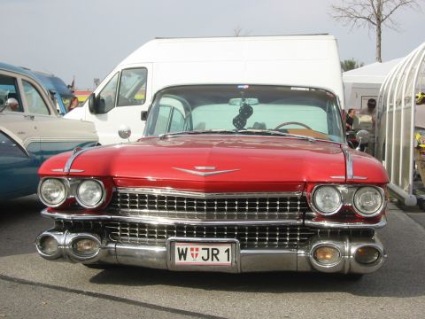 1992 Ford Crown Victoria - A red 1959 Cadillac Eldorado is parked in front of a white van, displaying its distinctive grille and headlights.