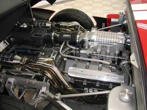 1985 Ford Bronco - Close-up of a supercharged engine, a prominent "POWERED BY FORD" inscription on the valve cover.
