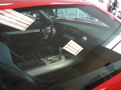 1985 Ford Bronco - Interior view of a red car a custom dashboard with five circular gauges and a prominent floor shifter.
