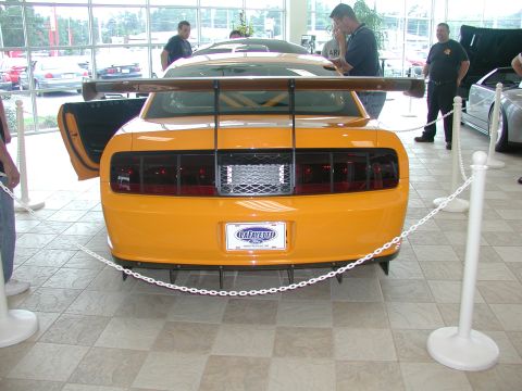 1985 Ford Bronco - A yellow sports car with a large rear spoiler and custom diffuser is displayed indoors.