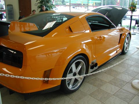 1985 Ford Bronco - Custom orange sports car with hood open, parked indoors.