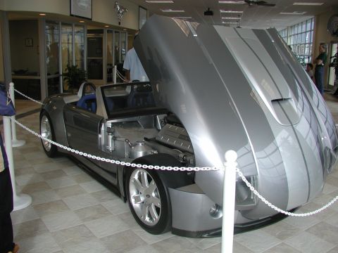 1985 Ford Bronco - This silver convertible, displayed indoors, features racing stripes and its hood is open to reveal the engine.