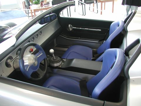 1985 Ford Bronco - The interior features bright blue bucket seats and a minimalist dashboard with a manual transmission.