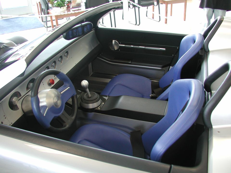 Interior of a custom car with blue racing seats, a blue steering wheel, and a manual shifter