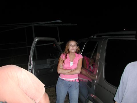 1985 Ford Bronco - A woman poses by an SUV at night, with a watermark visible on the lower right corner of the image.