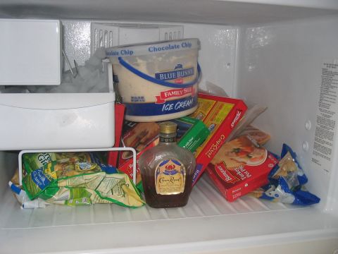 1988 Ford Bronco - The inside of a refrigerator is filled with various frozen food items and a bottle of liquor.