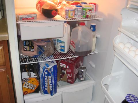 1988 Ford Bronco - A refrigerator is stocked with various food and beverage items, including milk, soda, beer, deli meat, and eggs.