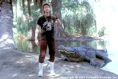 1993 Ford Bronco - A man stands next to an alligator on a sandy bank with trees and water in the background.