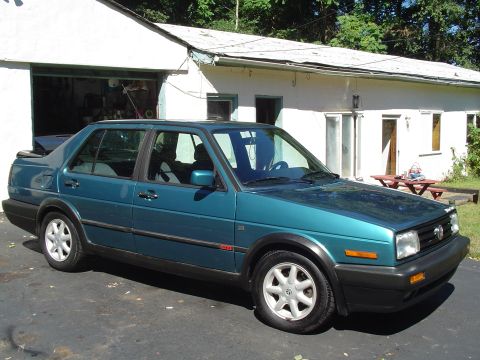 1992 Volkswagen Jetta - A teal 1992 Volkswagen Jetta is parked in front of a white house with a garage.