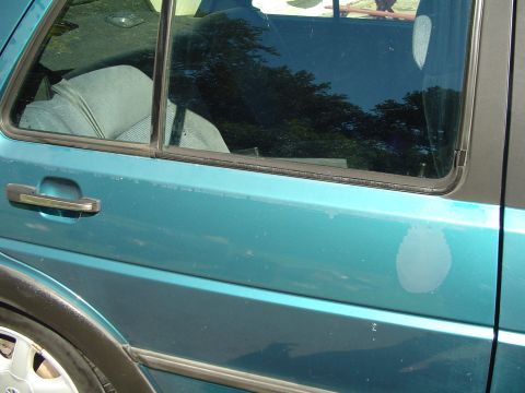 1992 Volkswagen Jetta - Side view of a teal 1992 Volkswagen Jetta, showing wear on the paint and a visible interior seat.