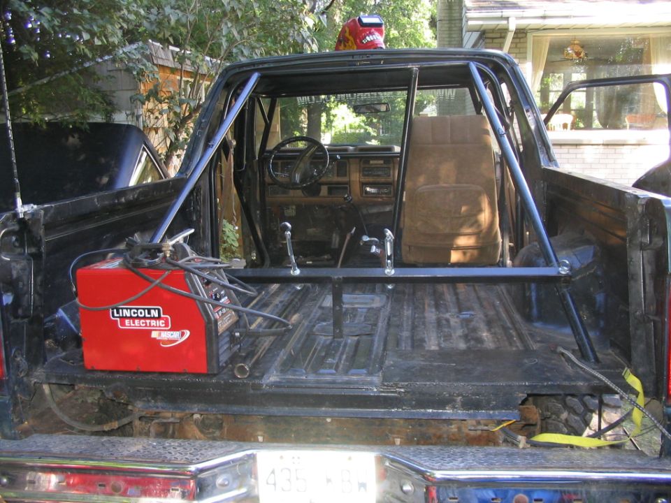 Roll cage fabrication inside a stripped Ford Bronco with Lincoln welder on tailgate