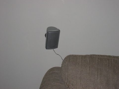 1988 Ford Bronco - A single gray speaker is mounted on the wall, with its wire running down towards a brown chair.