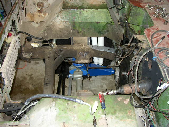 Engine bay of a vehicle undergoing repair, showing disassembled parts and wiring