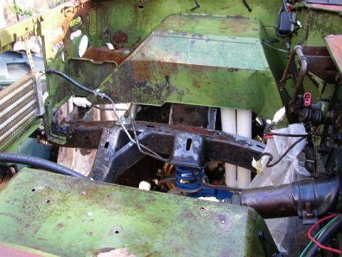 1995 Ford Bronco - The engine bay of a vehicle shows significant rust and wear, with exposed frame and suspension parts visible.