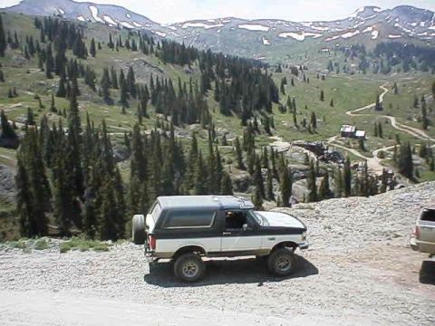 1993 Ford Bronco - Two-tone Ford Bronco parked on a mountain trail with a scenic backdrop.