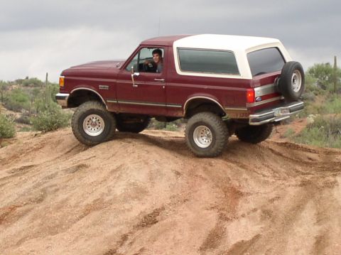 1990 Ford Bronco - This lifted 1990 Ford Bronco navigates a sandy incline, its off-road capabilities.