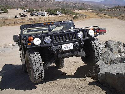 1988 Ford Bronco - A black Hummer H1 navigates a rocky obstacle course in a dry, hilly landscape.