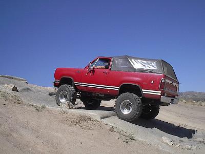 1988 Ford Bronco - A red 1978 Dodge Ramcharger is shown off-roading on a sunny day.