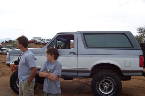 1992 Ford Bronco - A two-tone 1992 Ford Bronco is seen from the side with two people standing next to it in an outdoor setting.