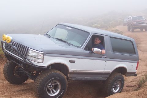 1992 Ford Bronco - Modified 1992 Ford Bronco navigates a foggy off-road trail with another vehicle following.